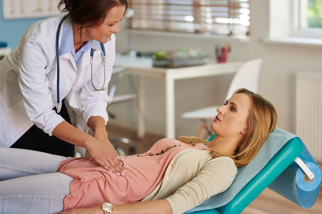 A doctor examines a patient's abdomen, showing why the right diagnosis matters in IBS vs IBD.